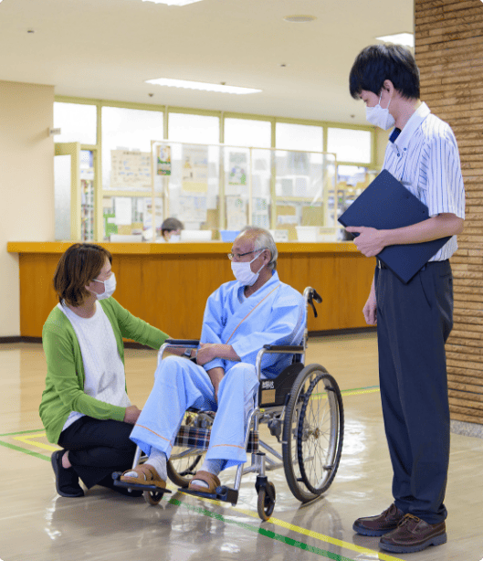 車椅子の患者に優しく話しかけるスタッフ