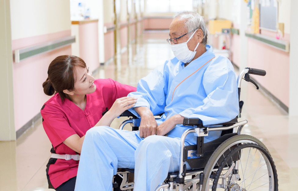 車椅子の患者に優しく語りかける光輝病院のスタッフ
